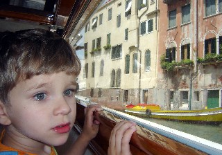 Child is shown staring out the water taxi in Venice. 