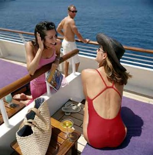 Guests talk over a divider at their SeaDream Balinese Beds on the top deck.